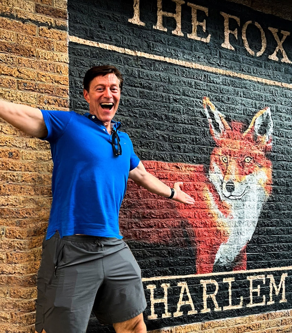John Fox posing in front of a mural of a fox